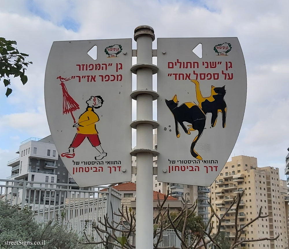 Holon - A sign directing to the story gardens Scattered from Kfar Azar, 2 cats on one bench